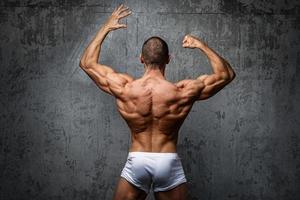 sexy und muskulöser mann, der gegen betonwand aufwirft foto