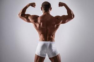 Schöner muskulöser Mann in Unterwäsche posiert auf grauem Hintergrund foto