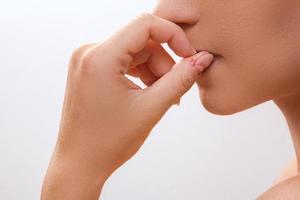 Nahaufnahme eines weiblichen Mundes, der sich in die Finger beißt foto