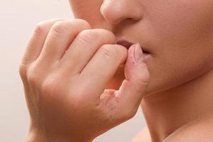 Nahaufnahme eines weiblichen Mundes, der sich in die Finger beißt foto
