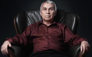 Porträt eines ernsthaften älteren Mannes im Sessel foto