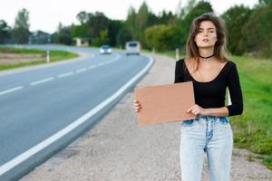 Tramper auf der Straße hält ein leeres Pappschild foto