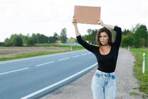 Tramper auf der Straße hält ein leeres Pappschild foto