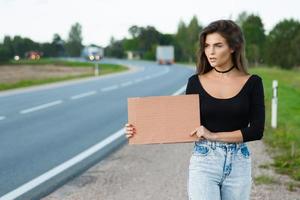 Tramper auf der Straße hält ein leeres Pappschild foto