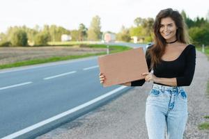 Tramper auf der Straße hält ein leeres Pappschild foto