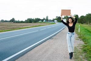 Tramper auf der Straße hält ein leeres Pappschild foto