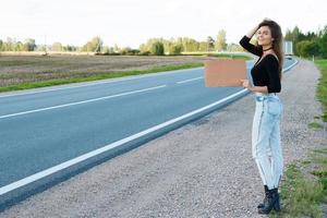 Tramper auf der Straße hält ein leeres Pappschild foto