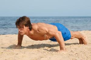 muskulöser Mann während seines Trainings am Strand foto