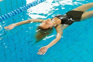Schwimmerin schwimmt auf dem Rücken im Pool foto