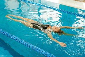 Schwimmerin schwimmt auf dem Rücken im Pool foto