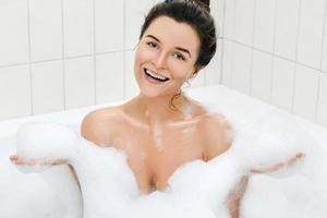 Frau nimmt ein Bad mit Schaum foto