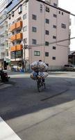 Eine nicht identifizierte Person auf einer Straße in Osaka fährt Fahrrad mit einem Stapel gebrauchter Dosen foto