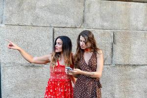 Zwei verlorene Mädchen, die mit einem Mobiltelefon interagieren, um Wegbeschreibungen in New York City zu erhalten foto