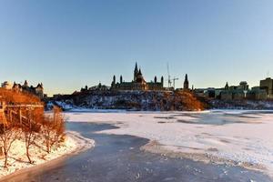 Parliament Hill und das kanadische Parlament in Ottawa, Kanada, über den zugefrorenen Fluss Ottawa im Winter. foto