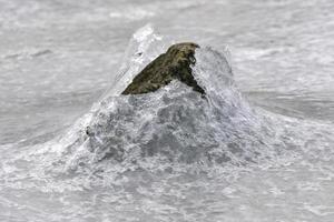 Felsen, der im Winter in Vagspollen auf den Lofoten, Norwegen, durch das Eis bricht. foto