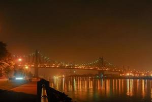 Blick auf die Queensboro Bridge von Roosevelt Island entlang der Ostseite von Manhattan in einer nebligen Nacht. foto