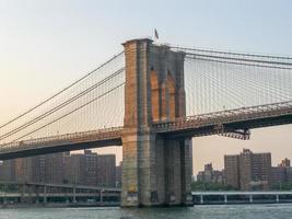 brooklyn bridge gegen die skyline von new york bei sonnenuntergang foto