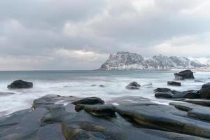 Wellen, die im Winter über den Strand von Utakleiv, Lofoten, Norwegen fließen. foto