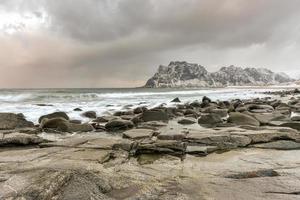 Wellen, die im Winter über den Strand von Utakleiv, Lofoten, Norwegen fließen. foto