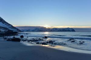 vikten beach auf den lofoten, norwegen im winter bei sonnenuntergang. foto