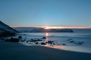 vikten beach auf den lofoten, norwegen im winter bei sonnenuntergang. foto