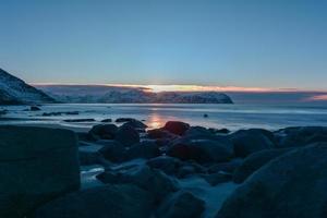 vikten beach auf den lofoten, norwegen im winter bei sonnenuntergang. foto