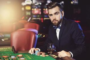 Schöner Mann, der im Casino Roulette spielt foto