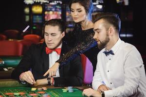 Schöne und reiche Leute, die im Casino Roulette spielen foto