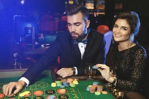 Schönes und reiches Paar, das im Casino Roulette spielt foto