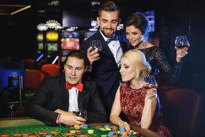 Junge und reiche Leute, die im Casino Roulette spielen foto