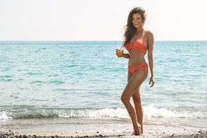 Frau am Strand mit einem Glas Cocktail foto