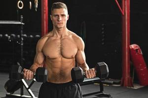 Junger gutaussehender Bodybuilder während seines Armtrainings im Fitnessstudio foto