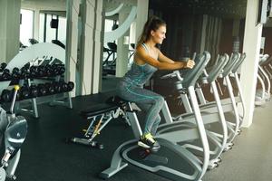 Frau auf stationärem Fahrrad im Fitnessstudio foto