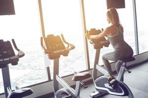 Frau auf stationärem Fahrrad im Fitnessstudio foto