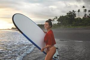 Junge und sexy Frau mit einem Longboard beim Surfen am Strand