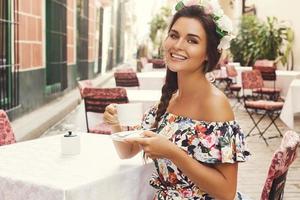 glückliche frau, die im straßencafé mit einer tasse heißen kaffee sitzt foto