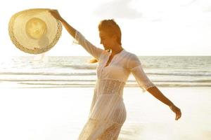 Porträt einer schönen jungen Frau mit breitkrempigem Hut am Strand foto