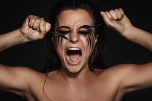 Frau mit Make-up-Flecken im Gesicht und kaputten Mascara-Bürsten foto