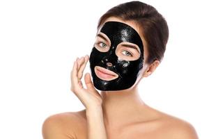 schöne Frau mit einer reinigenden schwarzen Maske auf ihrem Gesicht foto
