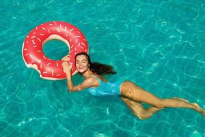 schöne Frau und aufblasbarer Schwimmring in Form eines Donuts foto