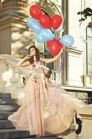 Frau in schönem Kleid mit vielen bunten Luftballons foto