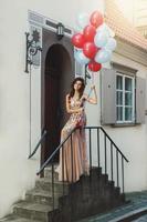 Frau in schönem Kleid mit vielen bunten Luftballons foto