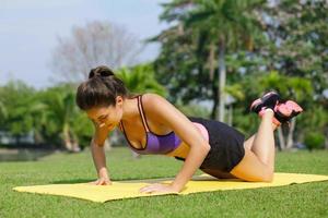 Frau, die im Park Knie-Liegestütze macht foto