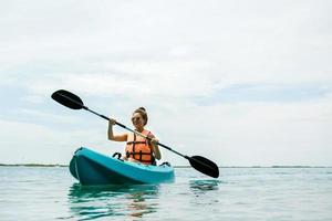 glückliche junge frau, die auf dem see kajak fährt foto