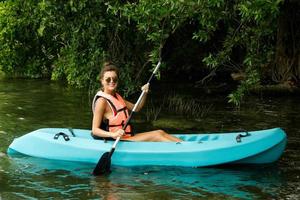 glückliche junge frau, die auf dem see kajak fährt foto