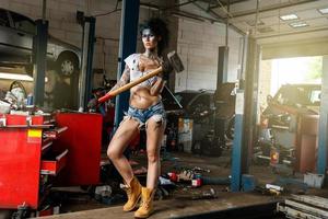 Mechanikerin in der Garage mit künstlerischem Make-up im Gesicht, stilisiert wie ein schmutziger Fleck foto