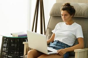 Frau im Schaukelstuhl mit Laptop-PC foto