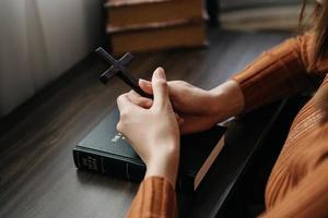 frau, die sitzt und die schriften studiert. das holzkreuz in den händen. christliche bildungskonzepte öffnen die heilige schrift foto