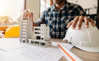 Geschäftsmann Hand arbeiten und Laptop mit auf Architekturprojekt auf der Baustelle am Schreibtisch foto