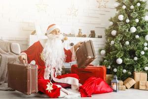 weihnachtsweihnachtsmann mit koffern bei sich zu hause. weihnachten, neujahr. foto